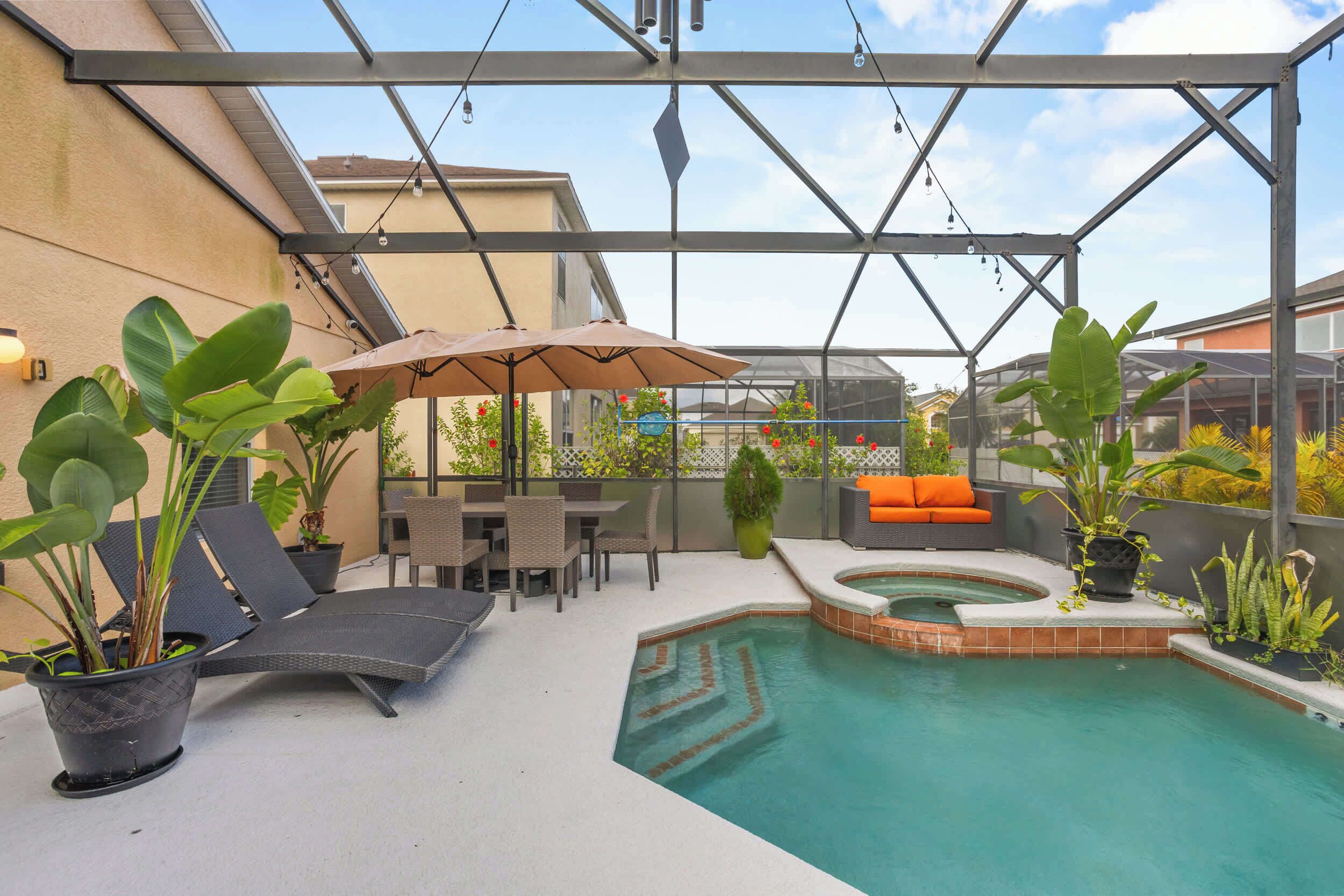 Uma área externa coberta com piscina, espreguiçadeiras e plantas em vasos.