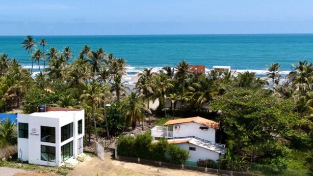 Une propriété située sur la côte, comprenant un bâtiment moderne aux lignes épurées, une maison traditionnelle et une vue sur l’océan.
