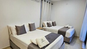 Une chambre d’hôtel avec deux lits, une table de chevet et une fenêtre avec des rideaux.
