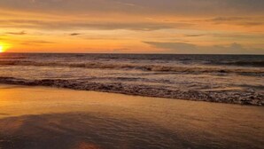 Une plage avec des vagues et un coucher de soleil.