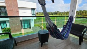 Un balcon avec un hamac, une petite table et une chaise.