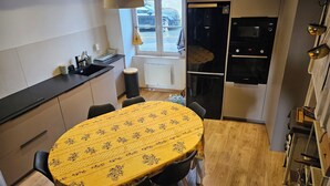 A compact kitchen with a dining table, a refrigerator, and a window with a view of a parked car. - 4-bedroom house, sleeps 8, lake view. (Château-la-Vallière)