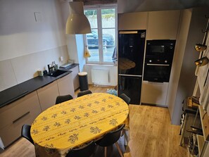 A compact kitchen with a dining table, a refrigerator, and a window with a view of a parked car. - 4-bedroom house, sleeps 8, lake view. (Château-la-Vallière)