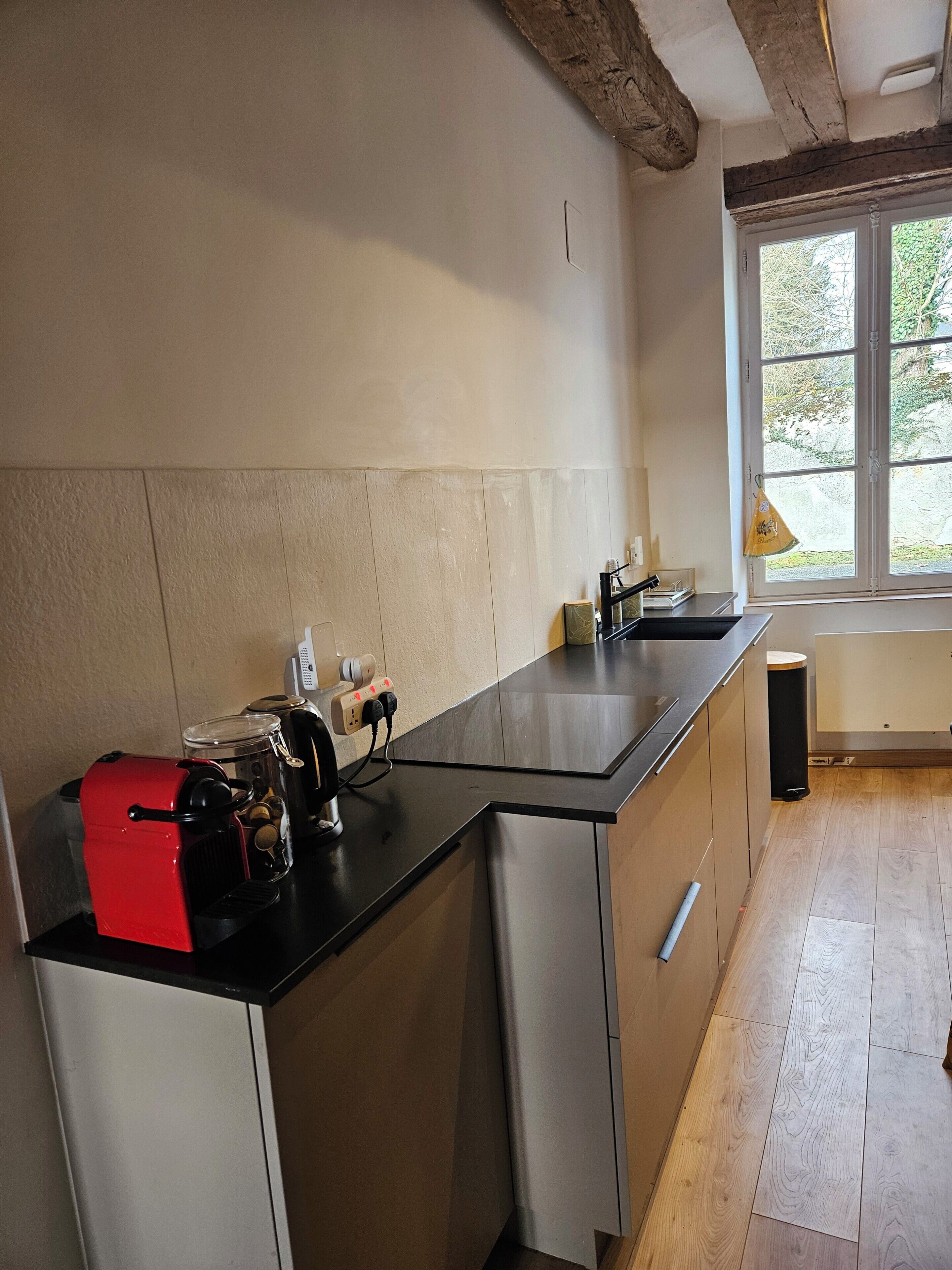 A modern kitchen with a black countertop, stainless steel appliances, and a window providing natural light.