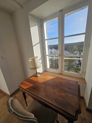 Ein Zimmer mit einem Holztisch, einem Stuhl und einem Fenster mit Blick auf eine Landschaft.