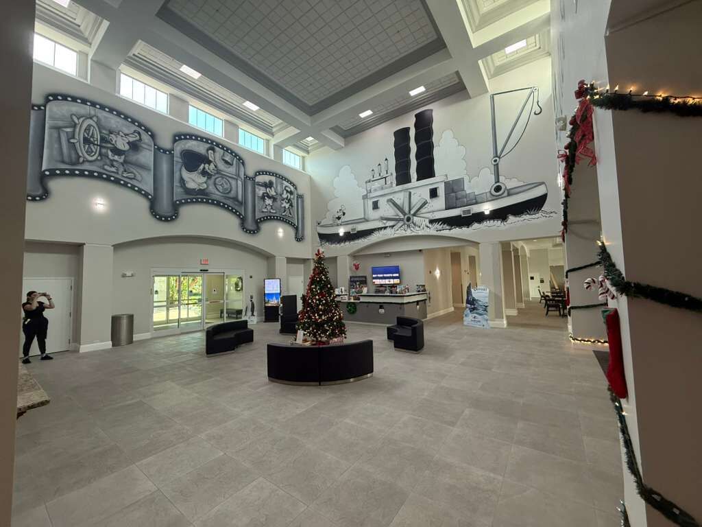 A spacious lobby with a Christmas tree, a large wall mural, and a reception desk.