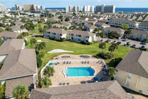 A residential area with a swimming pool surrounded by lounge chairs and palm trees. - Pool & Golf Course Views at Sandpiper Cove Unit 2014, Beach in Destin, FL (Destin)