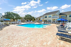 A swimming pool with lounge chairs and umbrellas, surrounded by a brick patio and a white fence. - Pool & Golf Course Views at Sandpiper Cove Unit 2014, Beach in Destin, FL (Destin)