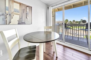 A room with a round table and two chairs, a sliding glass door leading to a balcony with outdoor furniture. - Pool & Golf Course Views at Sandpiper Cove Unit 2014, Beach in Destin, FL (Destin)