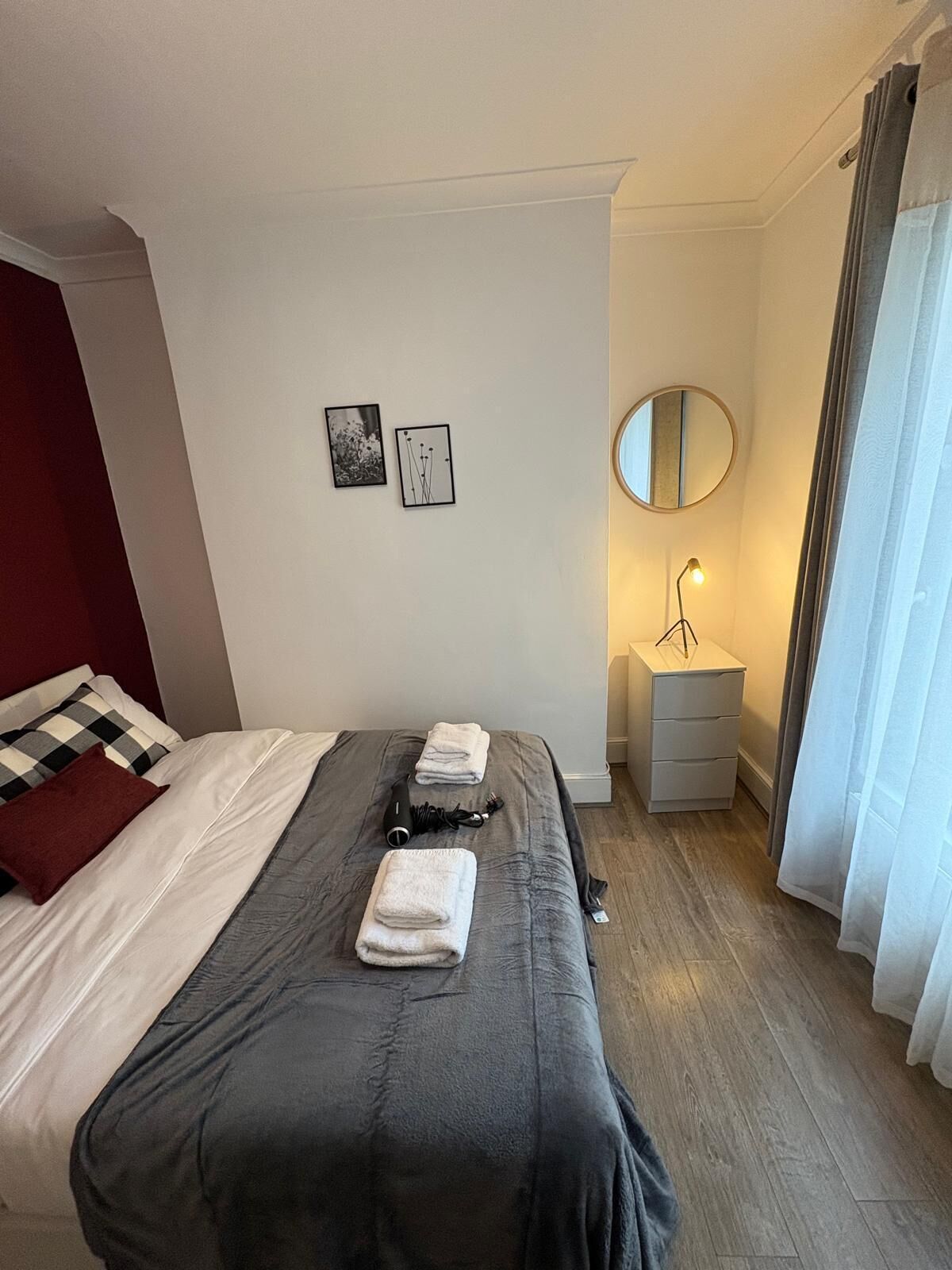 A neatly made bed with towels, a bedside lamp, and a small bedside table with a mirror.