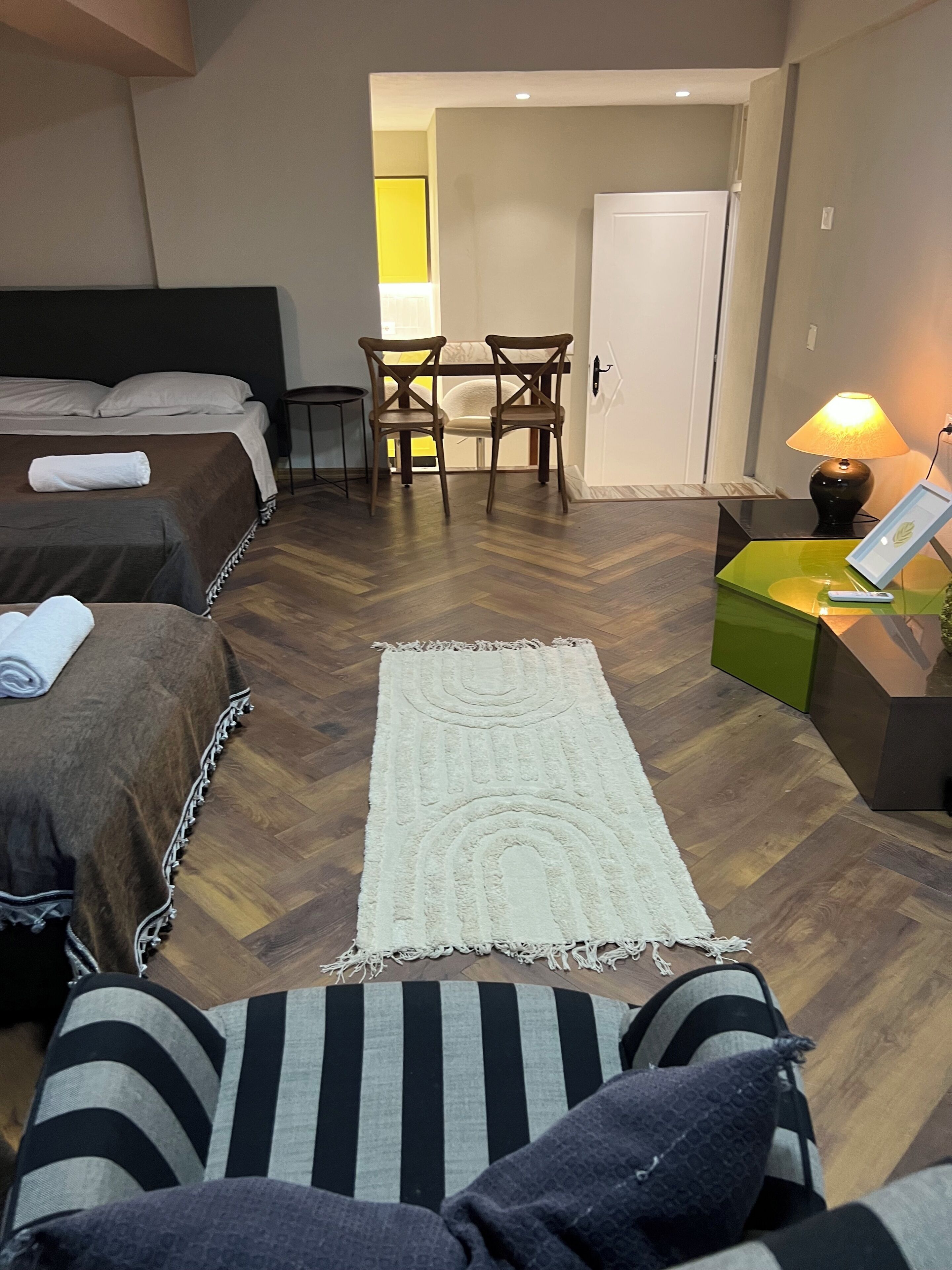 Ein Hotelzimmer mit Bett, Schreibtisch mit Lampe, Stuhl und Blick auf den Flur.