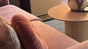 A modern living room with a sofa, a television, a small cabinet, and a vase with flowers.