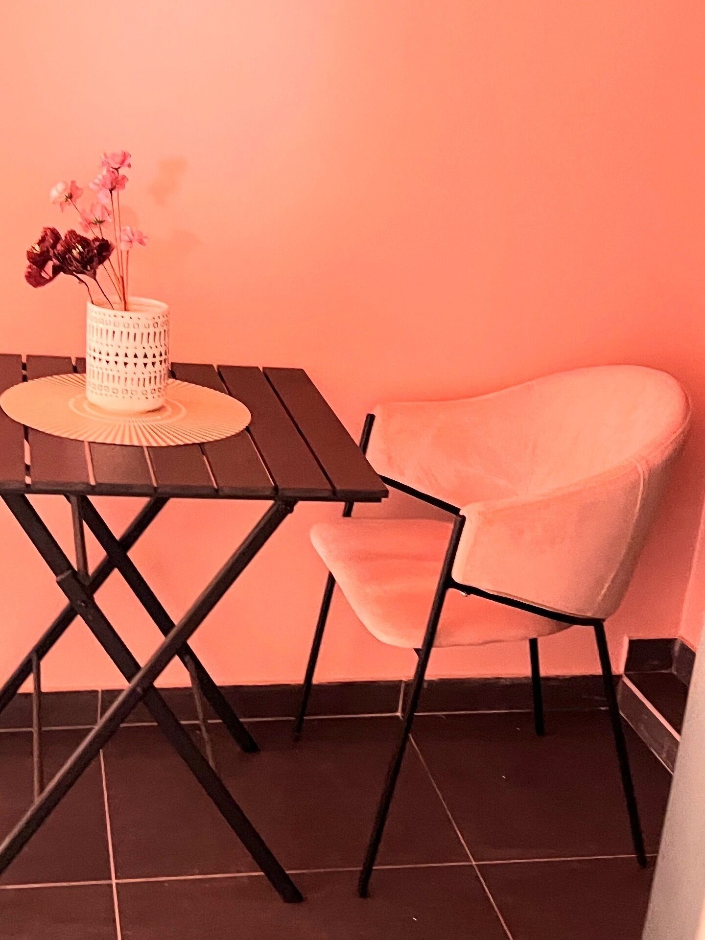 A small table with a white vase and a chair with a soft cushion.