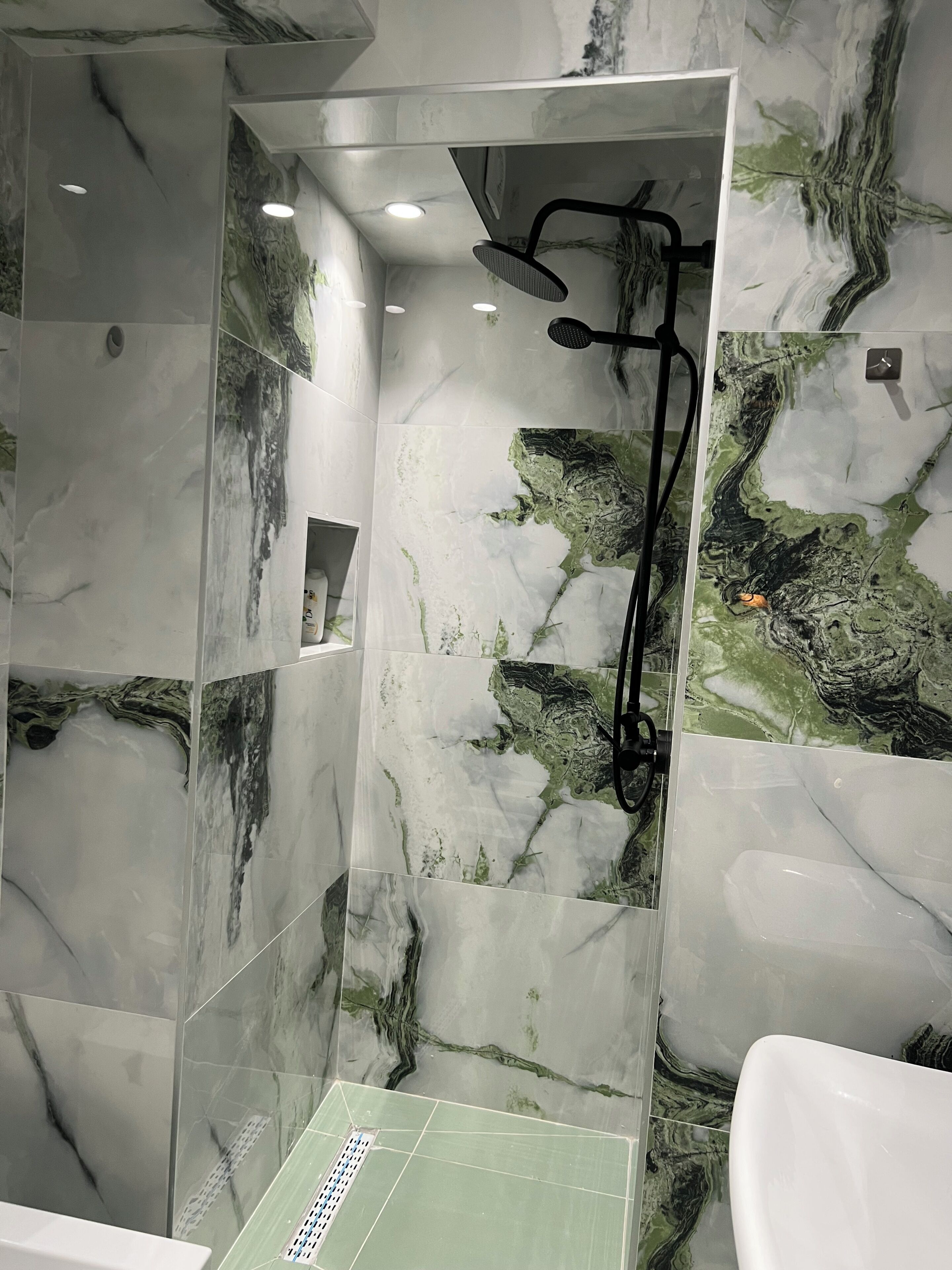 A bathroom with a shower area, a sink, and a mirror.
