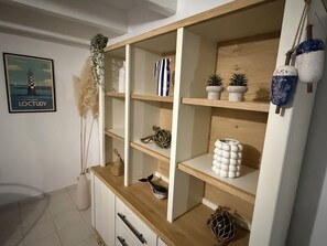 A modern interior with wooden shelves, decorative items, and a framed picture on the wall. - Renovated Breton house just 150 meters from the beach!  Enclosed Garden, Pets Welcome! (Loctudy)