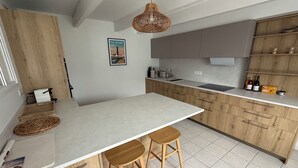 Cozinha moderna com uma ilha grande, armários de madeira e um lustre.