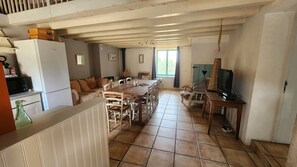 A spacious living area with a dining table, chairs, a sofa, and a television.