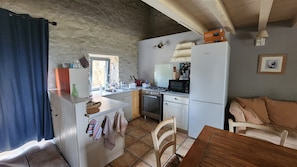 Une cuisine compacte équipée d’une cuisinière, d’un four à micro-ondes et d’un réfrigérateur. Un coin repas avec une table et des chaises est également disponible.