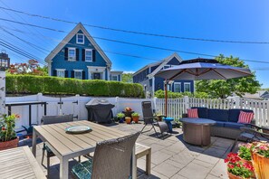 En uteplats med ett bord, stolar och en möblerad sittgrupp under tak.