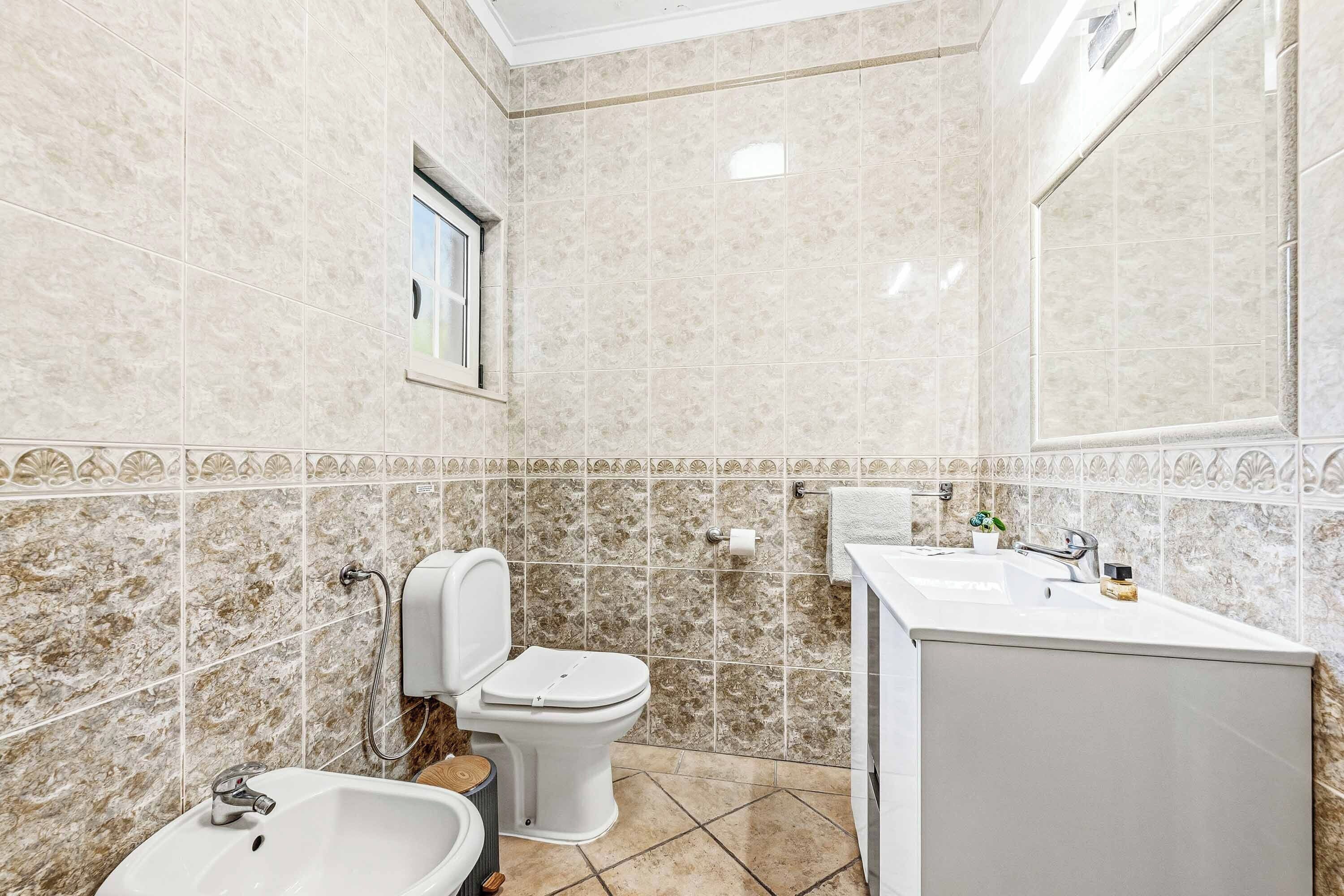A bathroom with a toilet, sink, and mirror.