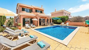 Ein zweistöckiges Haus mit Swimmingpool, Außenbereich und einer Terrasse.