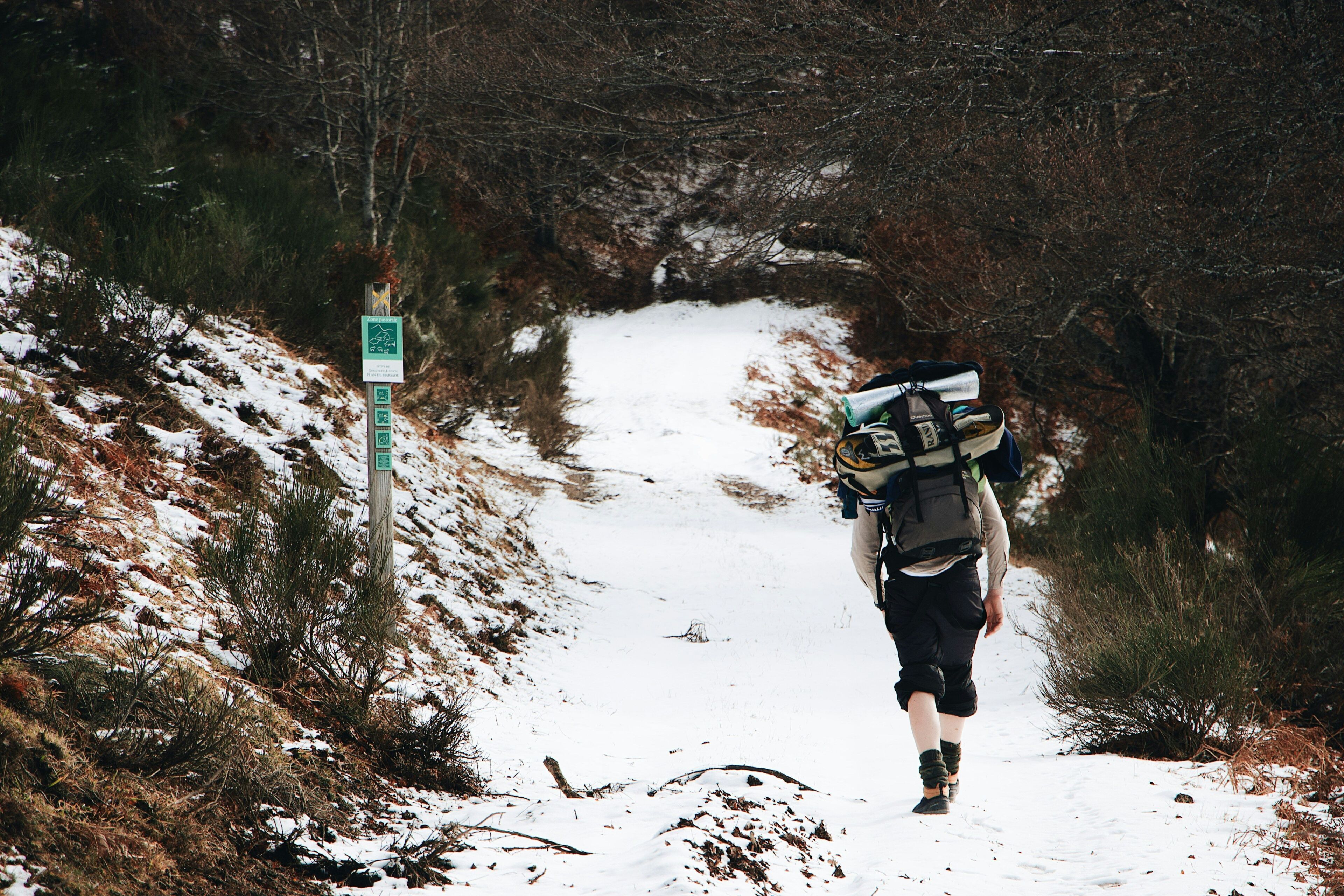 Una persona caminando sobre un sendero cubierto de nieve con una mochila.