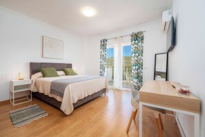 A bedroom with a bed, bedside table, desk, chair, and a window with curtains. -  Loule Hill - Lua Villa (Faro)