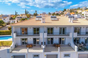 A multi-story building with balconies, a swimming pool, and solar panels. -  Loule Hill - Lua Villa (Faro)