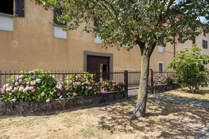 Un edificio con facciata beige, una recinzione in metallo nero e un albero di fronte.