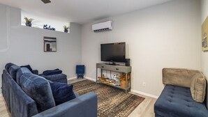 A living room with a sectional sofa, a television, and a small table.