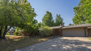 A residential property with a garage, a driveway, and mature trees.