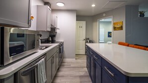 A modern kitchen with stainless steel appliances, a white countertop, and a blue cabinet. - Charming Casita | Couple Haven | Walk to OU Campus (Norman)