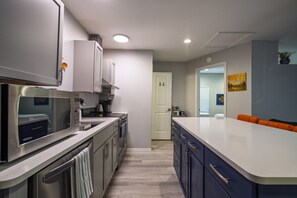 Una cocina moderna con electrodomésticos de acero inoxidable, una encimera blanca y un armario azul.