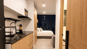 A modern kitchen with a black countertop, wooden cabinets, and a view of the city at night. - Apartment with incredible city view (Bogotá)