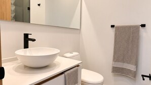 A modern bathroom with a white sink, toilet, and a large mirror. - Apartment with incredible city view (Bogotá)
