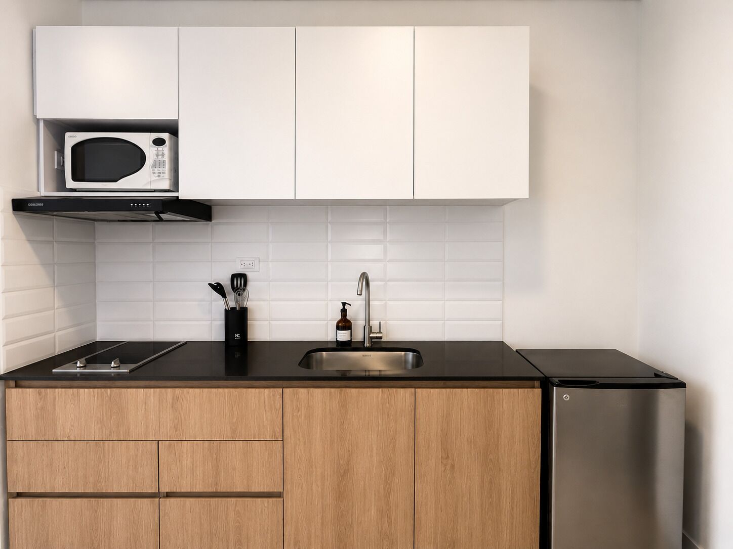 A modern kitchen with white cabinets, a stainless steel sink, a microwave, and a built-in oven.