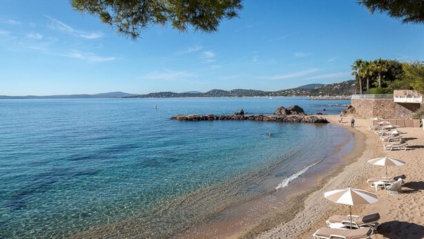 A beach with clear water, a rocky outcrop, and beach chairs with umbrellas. - The Nathéa Suite, 10 minutes from Sainte-Maxime (Roquebrune-sur-Argens)