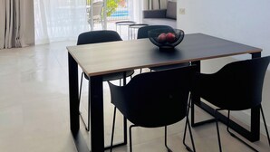 Un'area pranzo con tavolo, sedie, una ventola a soffitto e vista all'esterno.