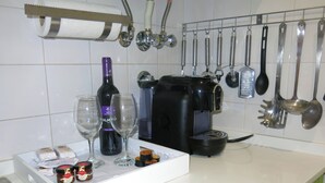 Une cuisine équipée d’une machine à café, d’une bouteille de vin, de verres, de bocaux et de divers ustensiles sur le plan de travail.