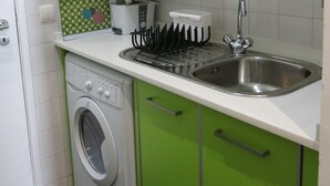 Une cuisine compacte équipée d’un four à micro-ondes, d’une cuisinière, d’un évier et d’un lave-linge.