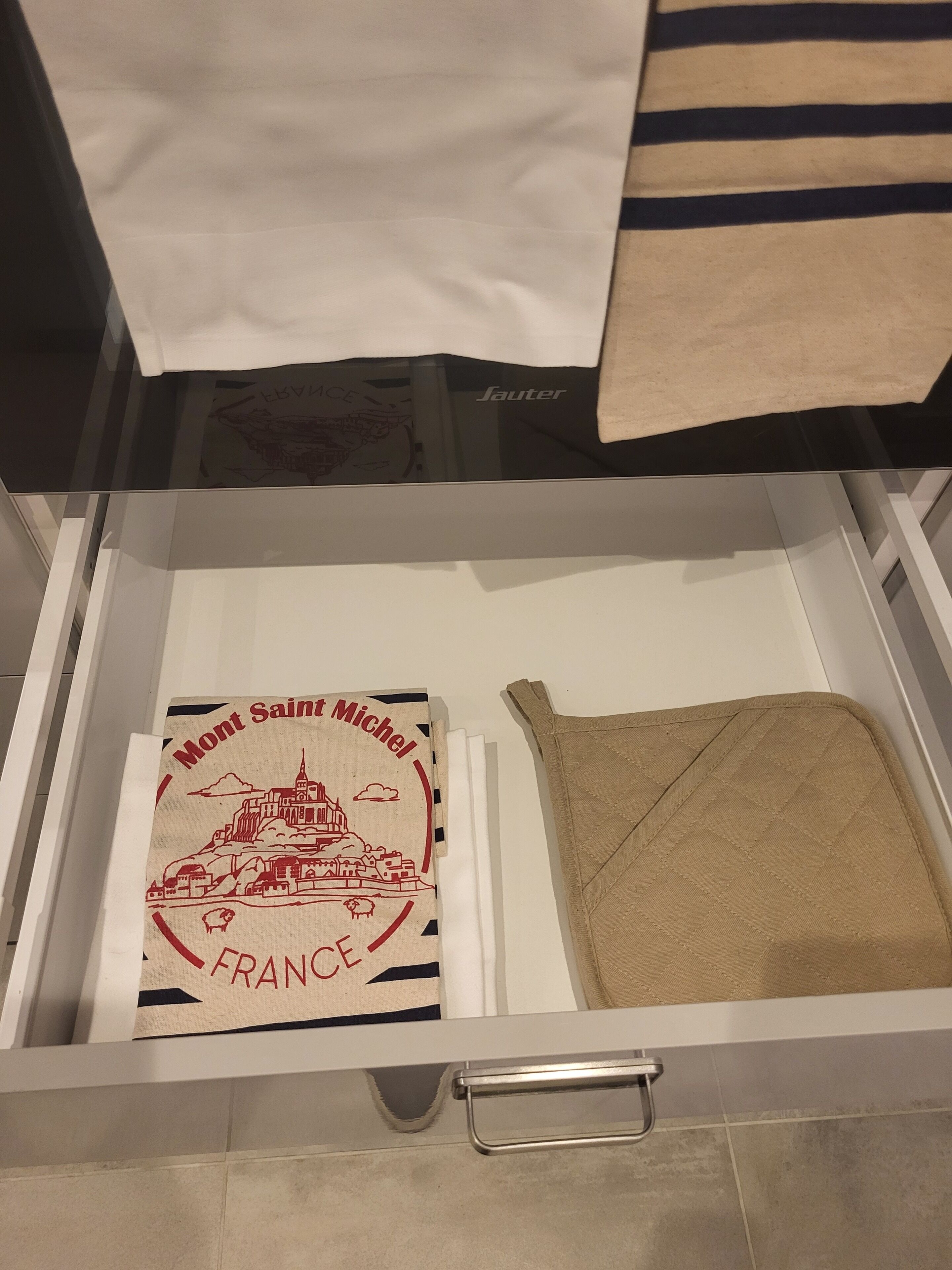A drawer with a map of France, a beige cloth, and a black and white striped item.