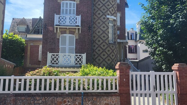 Un edificio con tetto a cono, pareti in mattoni e un recinto con staccionata bianca.