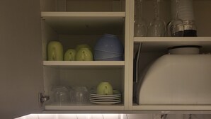 Una cucina con schienale in marmo, un lavello e un mobile contenente piatti e bicchieri.