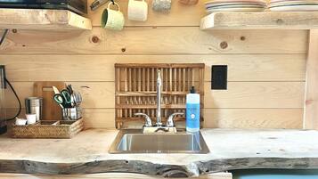 A kitchen with a wooden theme, featuring a microwave, a sink, and a dish soap bottle.