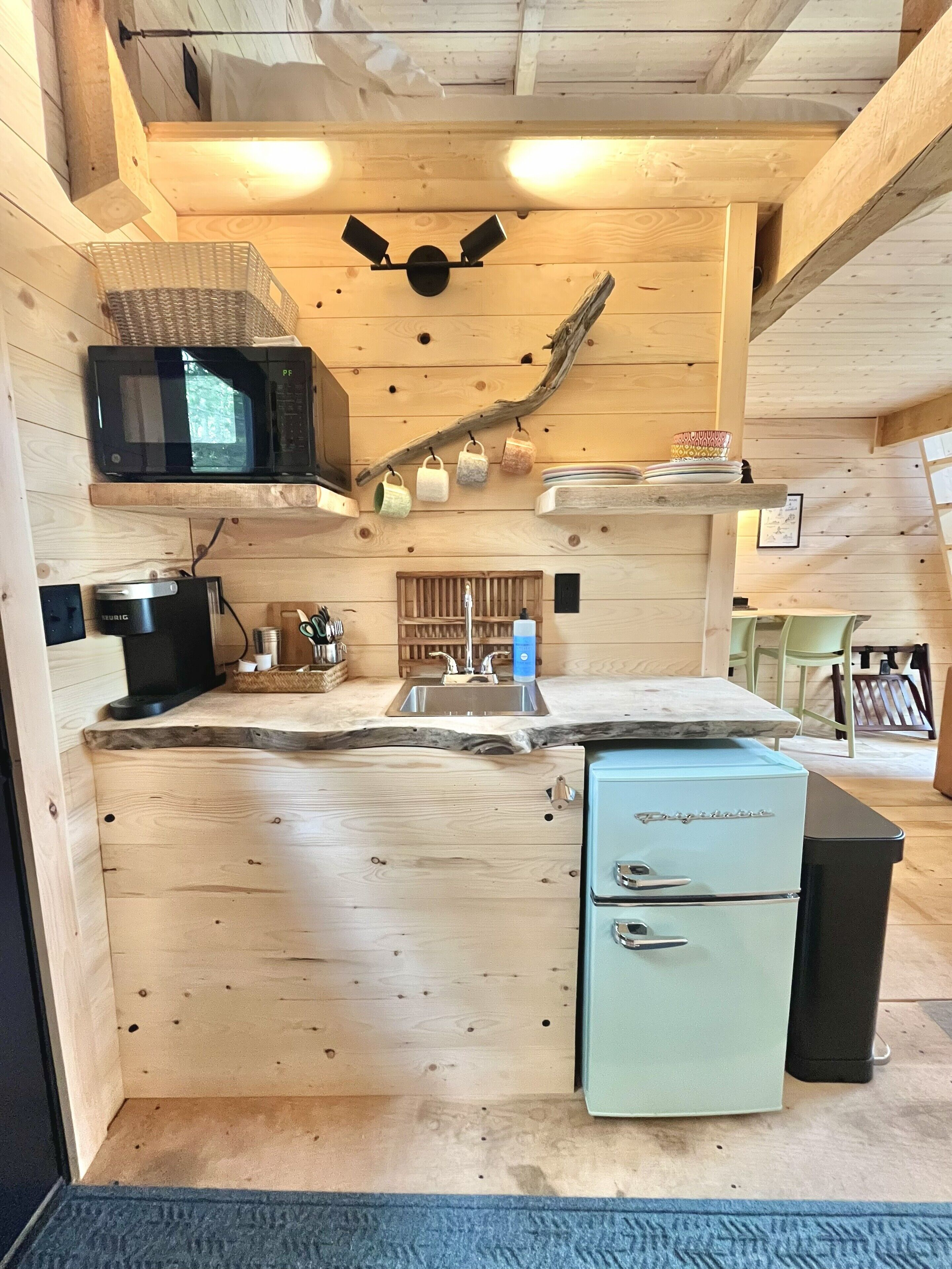 A compact kitchen with a microwave, sink, and vintage refrigerator.