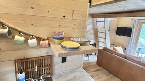 Una cocina pequeña con un lavamanos, un refrigerador compacto y techo de madera.