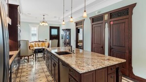 A kitchen with a granite countertop, dark wooden cabinets, and pendant lighting. - "CRAWL" off DUVAL Cottage—only 50 short Steps to the FUN!! (Key West)
