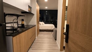 Moderni keittiö, jossa on keskeinen saareke, ruokailutila sekä makuuhuone, josta on näkymä kaupunkiin.