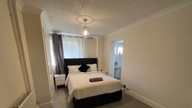 Un dormitorio con cama, mesita de noche y lámpara de techo.