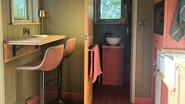 A compact kitchen with a sink, a window, and a bar stool. - Shepherd's Hut with mountain and valley views on the Mach Loop flightpath (Dolgellau)